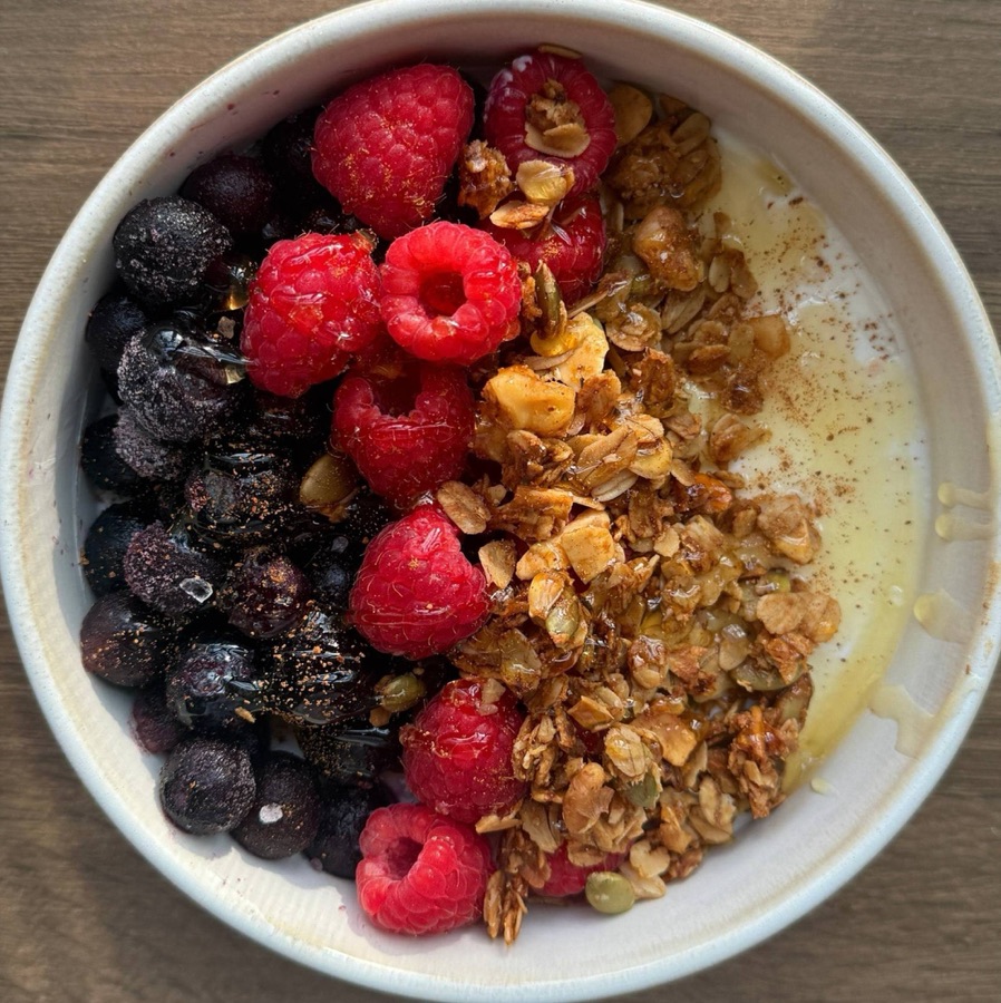 Bowl of yogurt with raspberries, blueberries, granola and honey